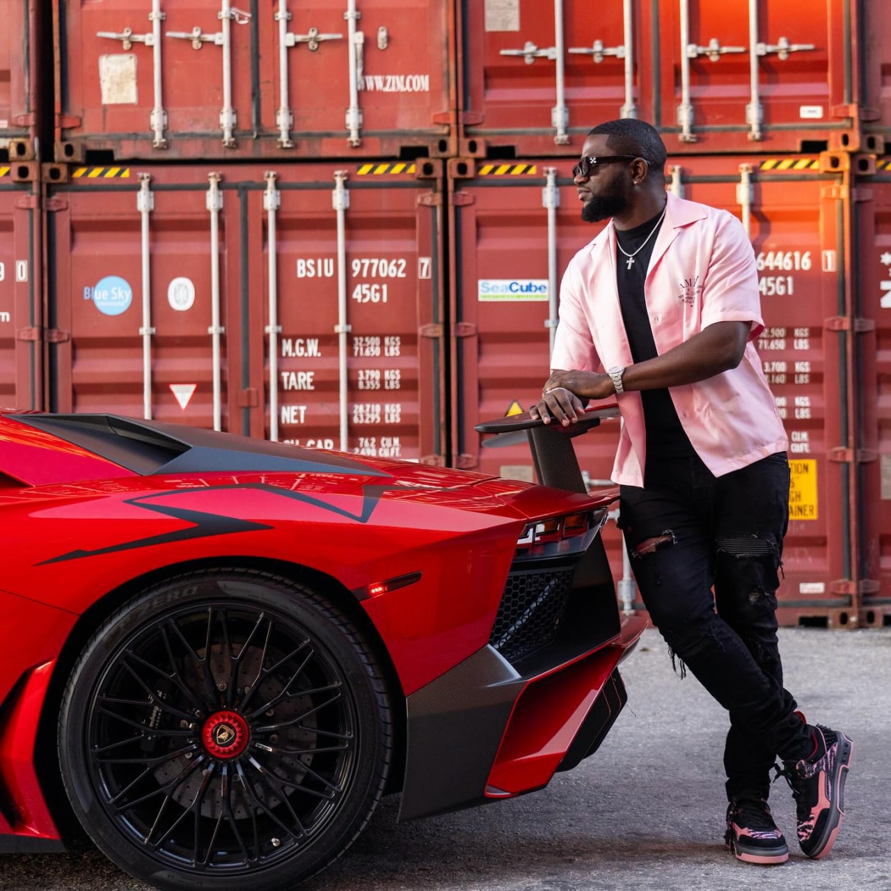Walter Weekes in pink shirt and sunglasses standing next to red Lamborghini