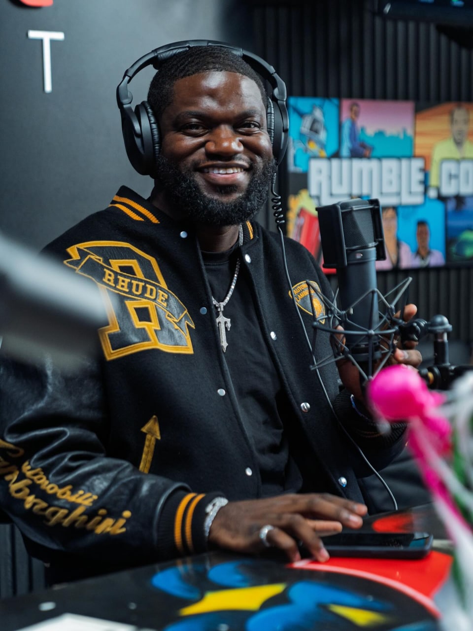 Walter Weekes in podcast studio wearing RHUDE jacket with headphones, big smile
